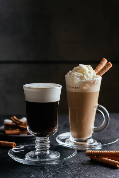 black coffee glass cup and cappuccino with whipped cream and sweet sticks on rustic table background - Фото, зображення