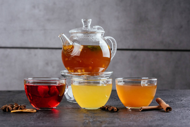 rakytník horký čaj skleněný hrnec se skleněnými poháry s malinami a citróny plátky na rustikálním pozadí - Fotografie, Obrázek
