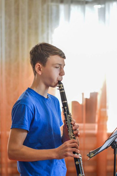 The guy plays the clarinet, looks at the music and plays music in a music school. - Fotoğraf, Görsel