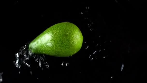 Falling of avocado on a black background. Slow motion. - Πλάνα, βίντεο