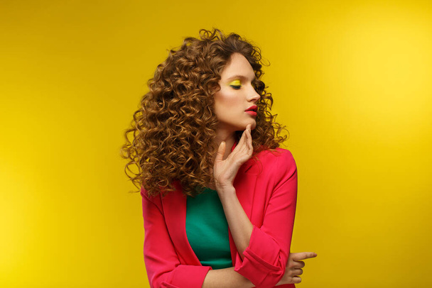 Close up fashion studio portrait of young beautiful women with curly hair.Nice girl with wavy hairstyle and bright make up isolated over yellow background.Beauty and hair care concept,yellow lifestyle - Fotografie, Obrázek