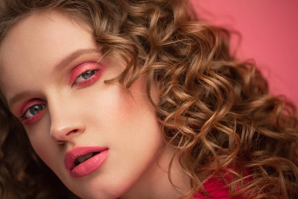 Close up fashion studio portrait of young beautiful women with curly hair.Nice girl with wavy hairstyle and bright make up isolated over pink background.Beauty and hair care concept,pink lifestyle - Φωτογραφία, εικόνα