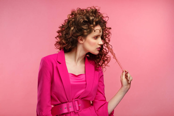 Close up fashion studio portrait of young beautiful women with curly hair.Nice girl with wavy hairstyle and bright make up isolated over pink background.Beauty and hair care concept,pink lifestyle - Foto, Imagem