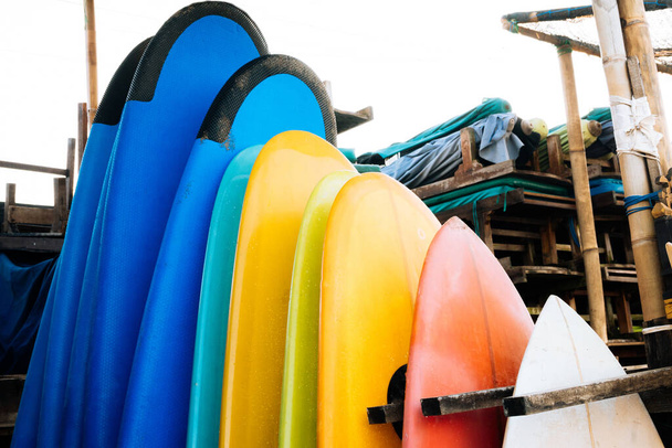 Set of colorful surfboard for rent on the beach. Multicolored surf boards different sizes and colors surfing boards on stand, surfboards rental place - Zdjęcie, obraz