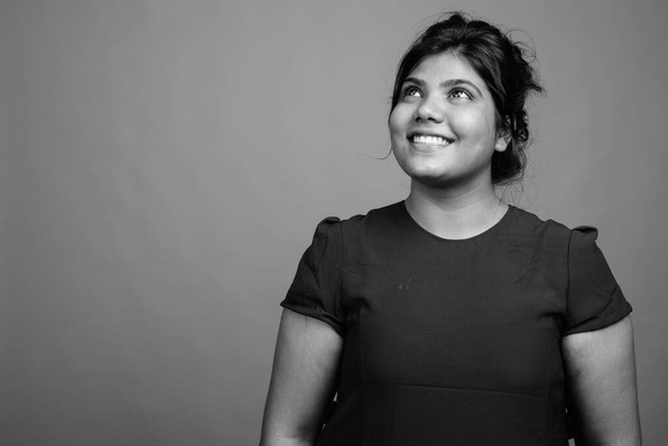 Estúdio tiro de jovem bela mulher indiana com sobrepeso contra fundo cinza em preto e branco - Foto, Imagem