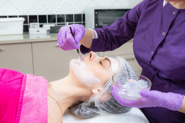 Face peeling mask, spa beauty treatment, skincare. Woman getting facial care by beautician at spa salon - Foto, Bild