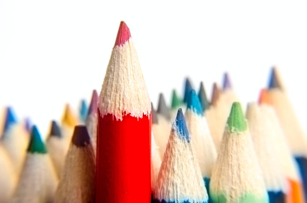Piros ceruza közelít. Piros színű ceruza állni a különböző színű ceruzák fehér háttér, elmosódott kép. Vezetői koncepció. Vissza az iskolába. Színes ceruzák elszigetelt fehér háttérrel. szelektív fókusz. - Fotó, kép