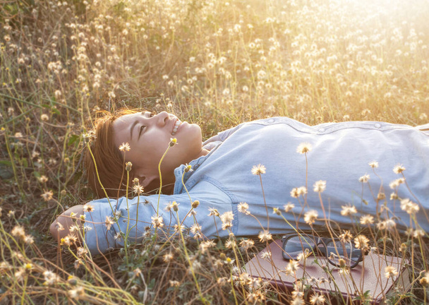 Genç bir kız çimlere uzanıp müzik dinliyor, yumuşak ve bulanık arka planda rahatlıyor. - Fotoğraf, Görsel