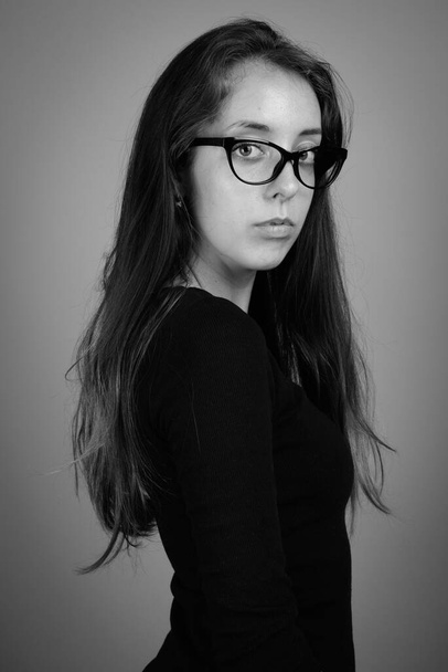 Studio shot van jonge mooie vrouw tegen grijze achtergrond in zwart-wit - Foto, afbeelding