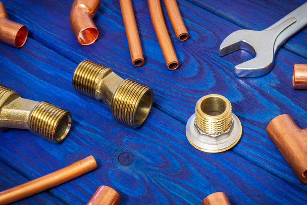 Raccordi per tubi in rame e strumento per la saldatura concetto di impianto idraulico o la riparazione di approvvigionamento idrico su tavole di legno blu vintage
 - Foto, immagini
