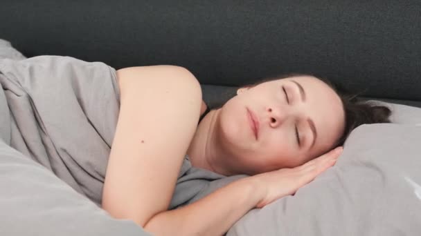 Close up of woman's face lying on bed with closed eyes. Young attractive female sleeping alone on bed. Portrait of charming girl sleeps on pillow - Video
