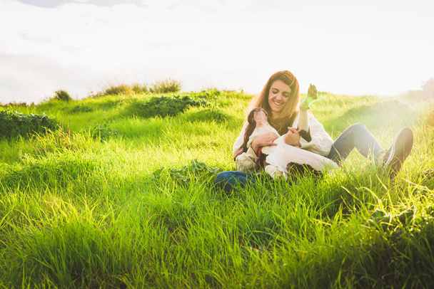 Young woman with white jersey and jeans playing with American Staffordshire terrier in the field - Foto, afbeelding