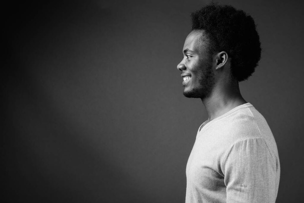 Studio shot of young handsome African man with Afro hair against gray background in black and white - Foto, Imagem