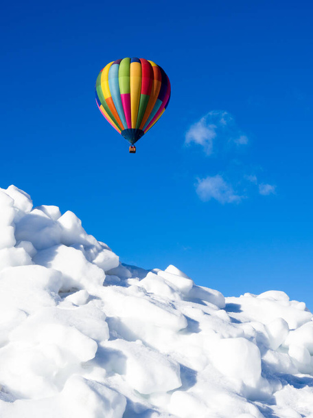 Kolorowy balon na gorące powietrze latający nad zaśnieżonym polem w zimie - Zdjęcie, obraz