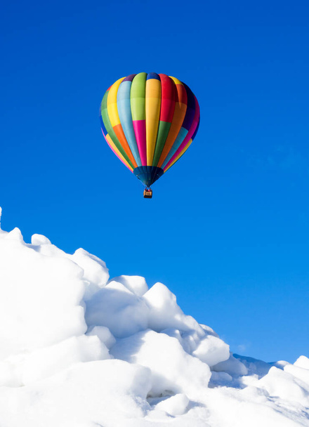 Colorful hot air balloon flying over snowy field in winter - Photo, Image