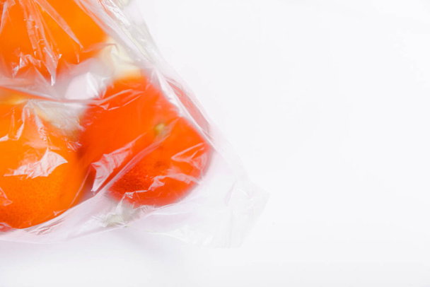 Mandarinas con una bolsa de plástico transparente sobre un fondo blanco. Copiar espacio
 - Foto, imagen