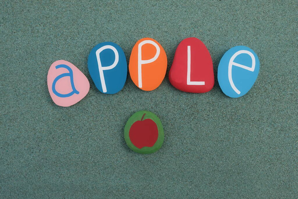 Μήλο, φρούτα και θηλυκό όνομα αποτελείται με πολύχρωμα γράμματα πέτρα πάνω από την πράσινη άμμο - Φωτογραφία, εικόνα