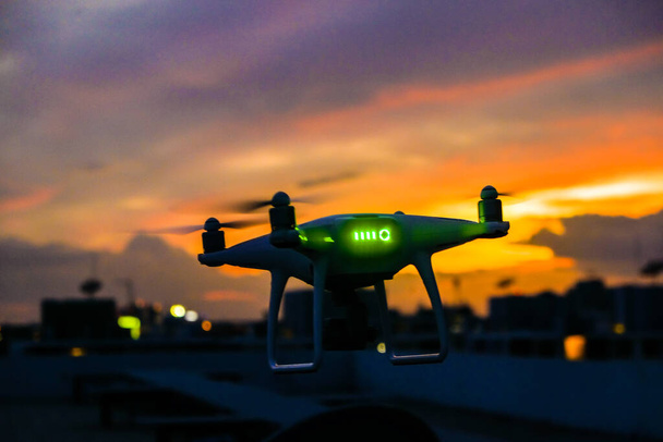 Quadcopter drón repül a város felett épület naplemente ég felhő modern közlekedés - Fotó, kép