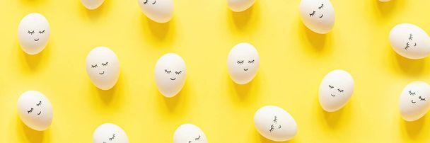 Creative easter eggs with cute face and sleepy eyes on pastel yellow background. Happy Easter concept. Flat lay, top view, mockup, template, overhead, copy space. - Foto, Imagen