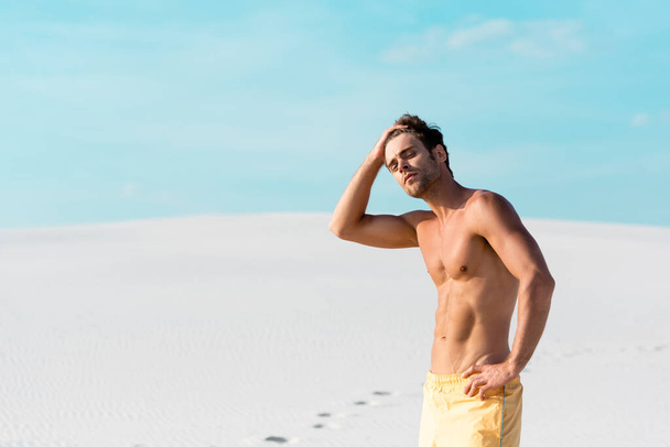man in swim shorts with muscular torso on sandy beach - Фото, зображення