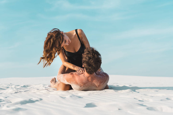 sexy jovem mulher sentado no namorado deitado no areia praia
  - Foto, Imagem