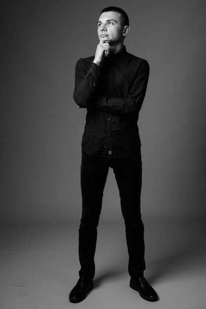 Studio shot de jeune homme d'affaires beau en chemise décontractée sur fond gris en noir et blanc - Photo, image