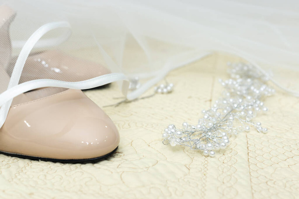 Γαμήλια παπούτσια κάτω από λευκό νυφικό πέπλο και διακόσμηση κοσμημάτων - Φωτογραφία, εικόνα