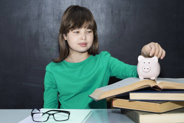 Teen puts coins in the piggy bank. The concept of paid education - Photo, Image