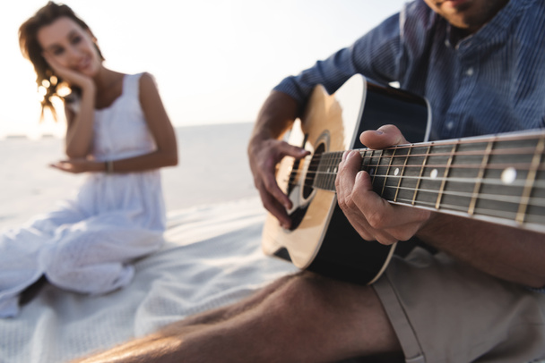 selektywne skupienie człowieka grającego na gitarze akustycznej do dziewczyny na plaży - Zdjęcie, obraz