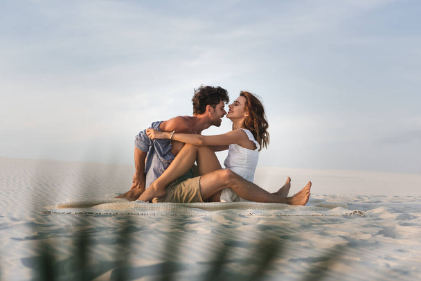 selective focus of passionate young couple kissing on blanket on beach - Фото, зображення