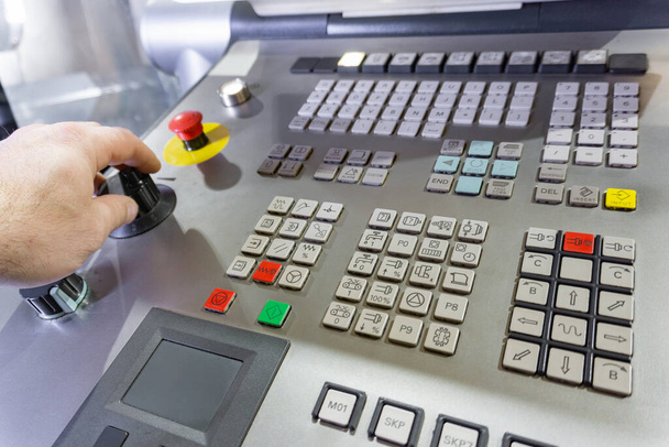 Il lavoratore commuta i pulsanti sul telecomando della macchina CNC, il controllo del centro di lavorazione. - Foto, immagini