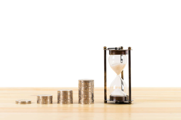 Coin stack and hourglass on wooden desk  on white background, time for saving concept - Photo, Image