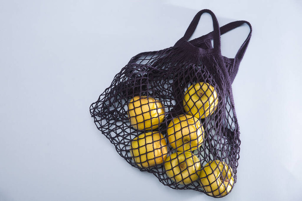 Blue string bag with green apple on a blue paper background - 写真・画像