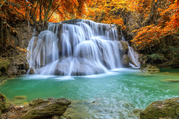 Beautiful and colorful waterfall in deep forest during idyllic autumn - Photo, Image