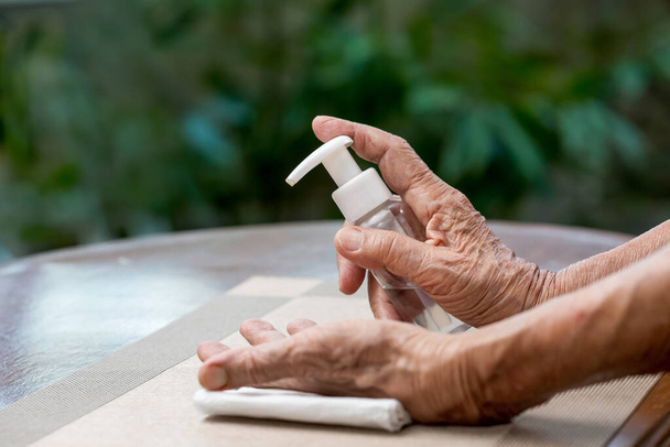 コロナウイルスから保護するのを助けるためにアルコールジェル洗浄手を適用する高齢女性covid-19 - 写真・画像