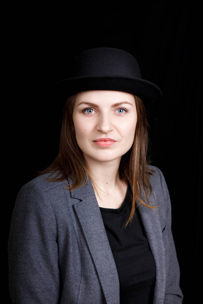 мила молода дівчина в капелюсі і сіра куртка на чорному тлі
 - Фото, зображення