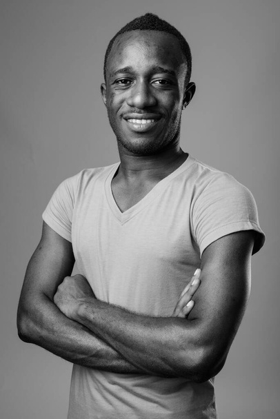 Studio shot of young African man against gray background in black and white - Photo, Image