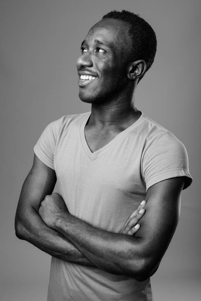 Studio shot of young African man against gray background in black and white - Foto, immagini