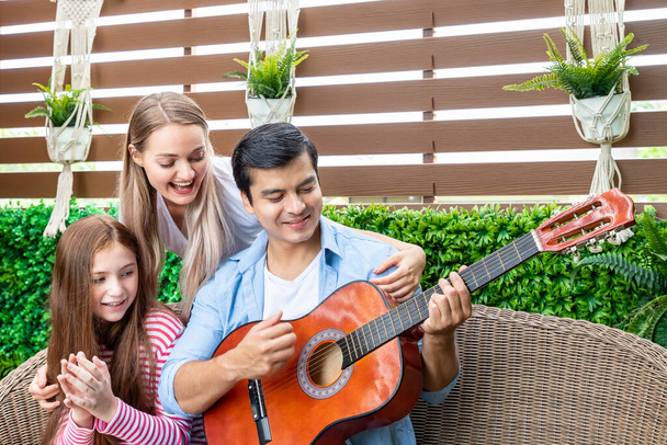 Gelukkige familie spelen gitaar, zingen, en genieten van muziek in de tuin thuis, familie relatie concept. - Foto, afbeelding