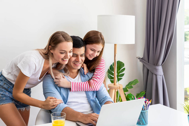 Gelukkige familie, vader moeder en dochter, met behulp van notebook computer samen, lachen en kijken naar het scherm - Foto, afbeelding