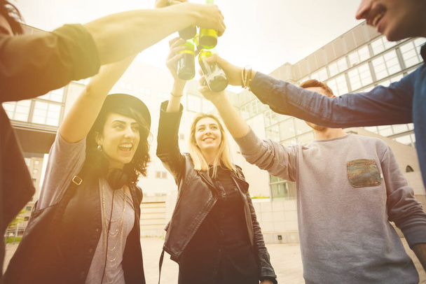 Grupa młodych przyjaciół wielorasowych na świeżym powietrzu wznoszących toast z butelką piwa - koncept towarzyski, celebracyjny, koncept wspólnoty - Zdjęcie, obraz