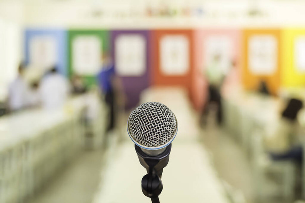 Микрофон над абстрактной размытой речью в зале семинаров или освещении конференц-зала в фоновом режиме выставочного центра, концепции бизнеса и образования
. - Фото, изображение
