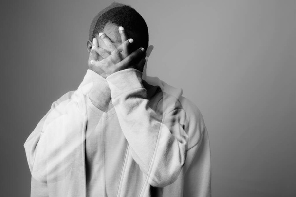 Plan studio de jeune homme africain portant un sweat à capuche sur fond gris en noir et blanc - Photo, image