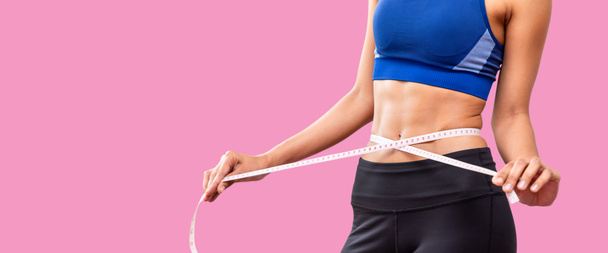 ピンクの背景にテープを測定する魅力的な女性の胴、減量と食事のコンセプト - 写真・画像