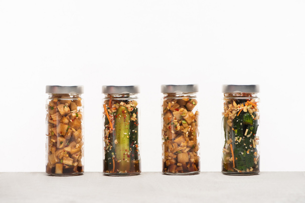 daikon radish and cucumber kimchi in jars isolated on white - Photo, Image
