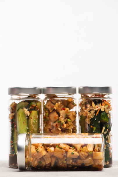 tasty daikon radish and cucumber kimchi in jars isolated on white - Fotoğraf, Görsel