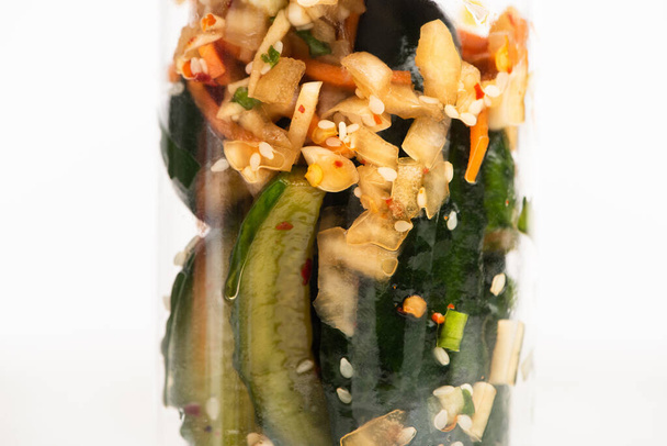 close up of tasty cucumber kimchi in jar isolated on white - Photo, Image