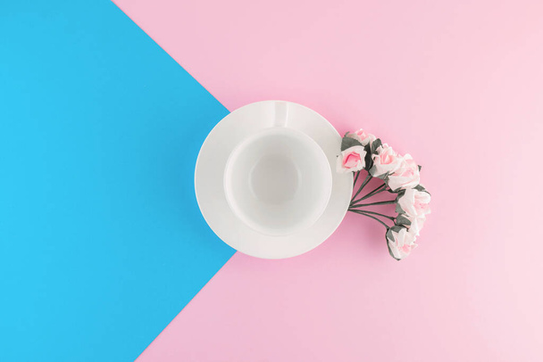 Empty coffee cup and flower on beautiful pink and bright blue pastel background. Top view. Flat lay. Template for design. - Photo, image