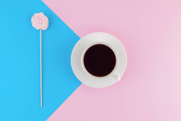 A cup of freshly brewed coffee on beautiful pink and bright blue pastel background. Fresh desserts. Meringue. Pink Chocolate. Top view. Flat lay.  - Fotó, kép