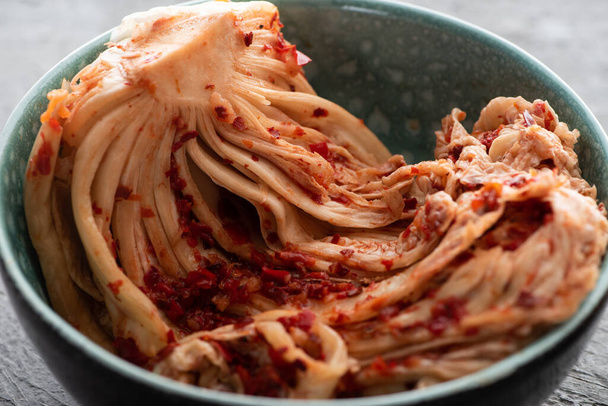 close up of bowl with tasty kimchi cabbage on concrete surface - Photo, Image